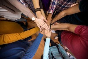 hands held in a circle at a meeting of an alumni program for teens