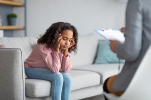 girl with head in hands on couch going through an anger management program