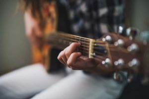 a teen learns to play the guitar as part of their music therapy for depression