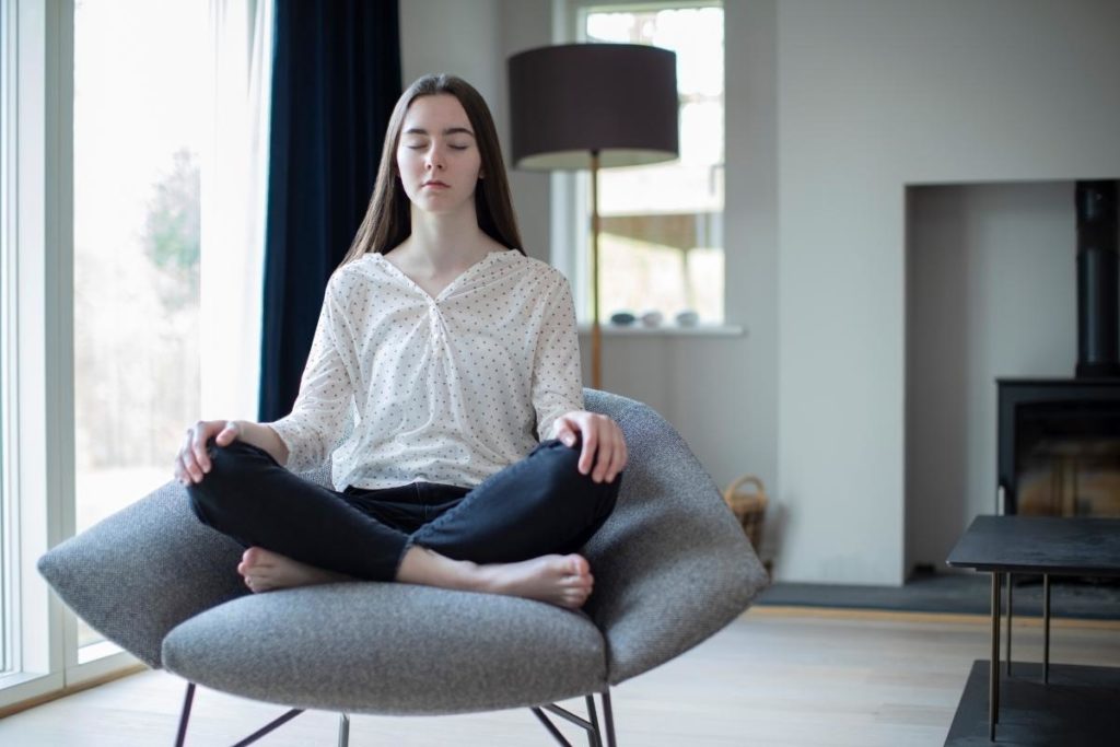 a teen meditates as part of meditation therapy in a calming room in her home to manage stress and anxiety