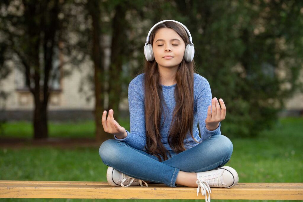 Young girl smiling while listening to a guided meditation to promote adolescent mental health