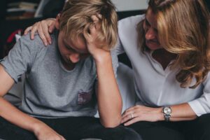 Young person experiencing anxiety symptoms with mother offering comfort after learning about how to recognize anxiety in your teen