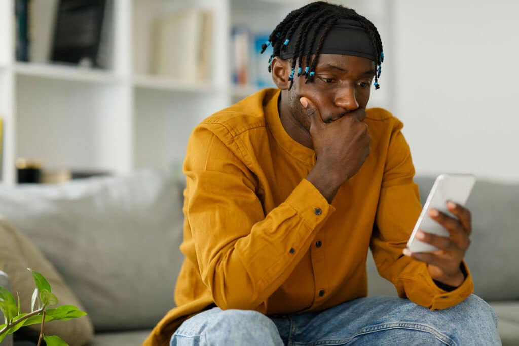 Young person sitting on couch looking at phone considering how social media affects teen mental health