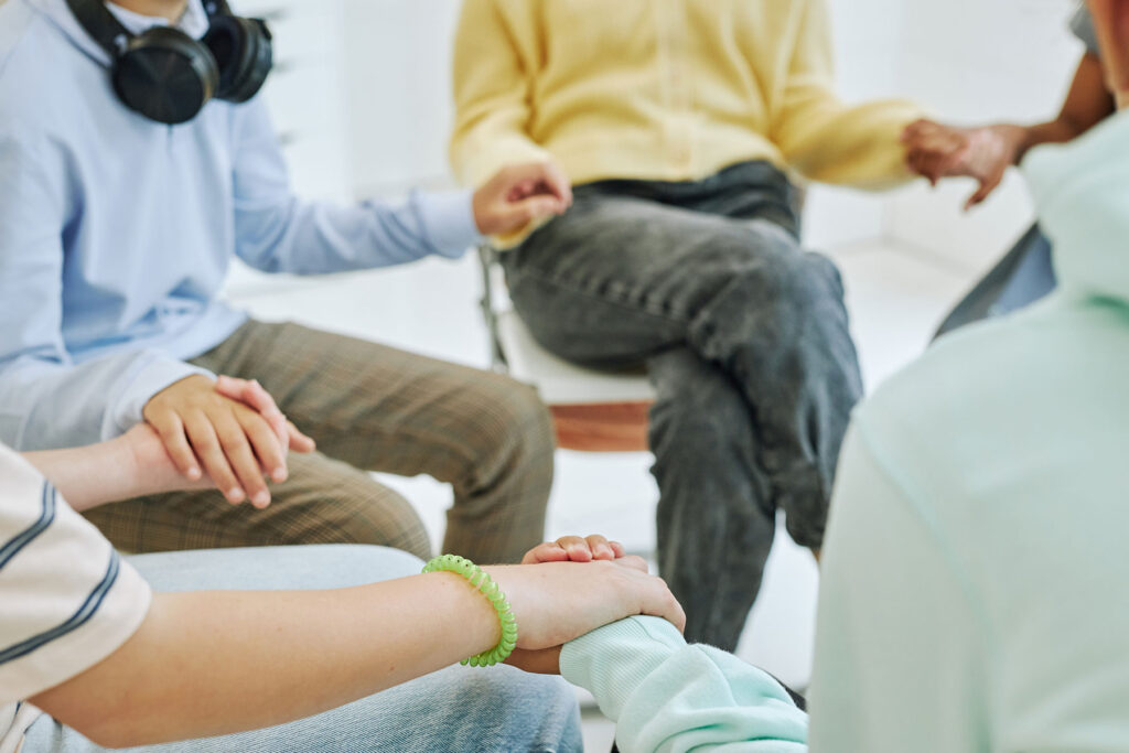 people joining hands in group therapy while reaping the benefits of teen relationship counseling