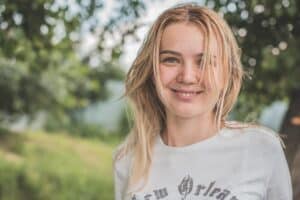 young teenager smiling on beautiful sunny day in the park while reaping benefits of psychotherapy