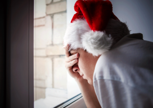depressed person wearing santa hat needing tips for coping with holiday stress and anxiety