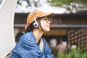 teen listening to music on headphones while spending time outdoors experiencing the benefits of music therapy